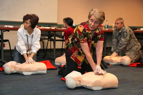 Adults practicing chest compressions on CPR manikins in a classroom