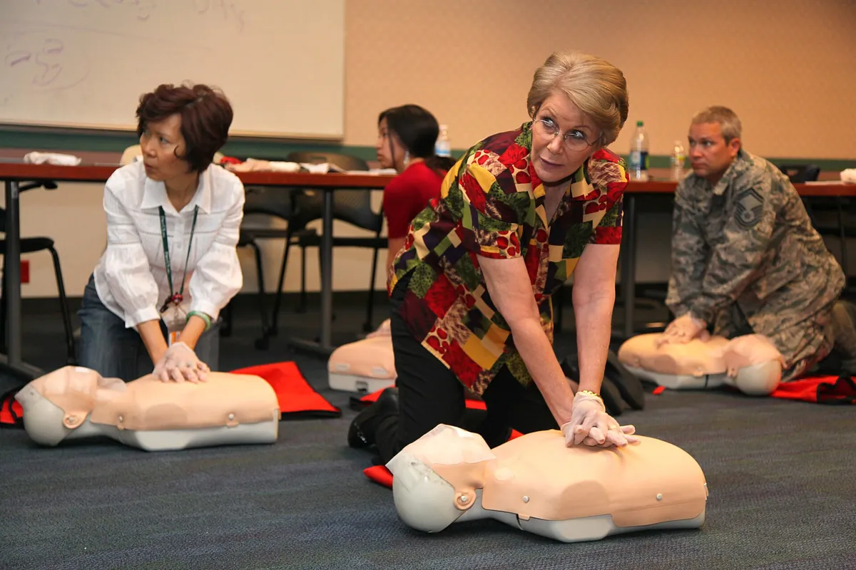 Adults practicing chest compressions on CPR manikins in a classroom