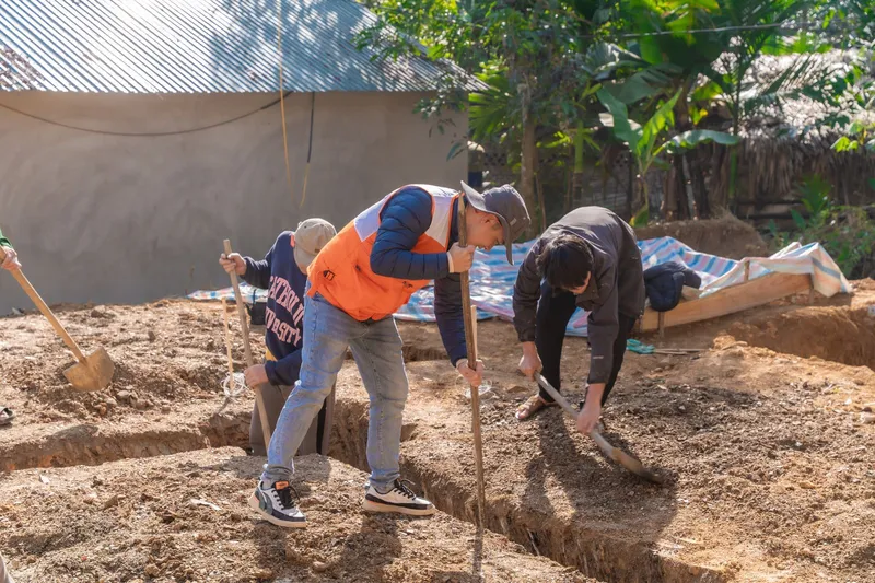 Crew digging and leveling trenches on a dirt site