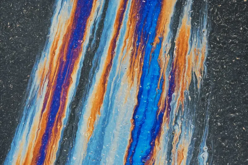 Oil sheen from a spill spreading across the ground