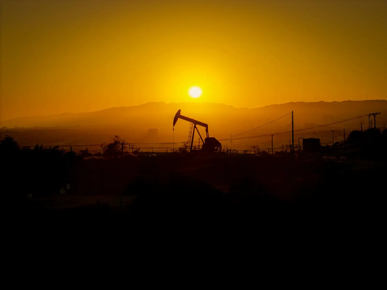 Pumpjack silhouetted against a hazy West Texas sunset