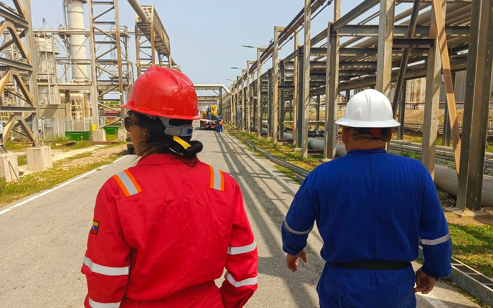 Workers in hard hats and coveralls walking through an industrial plant