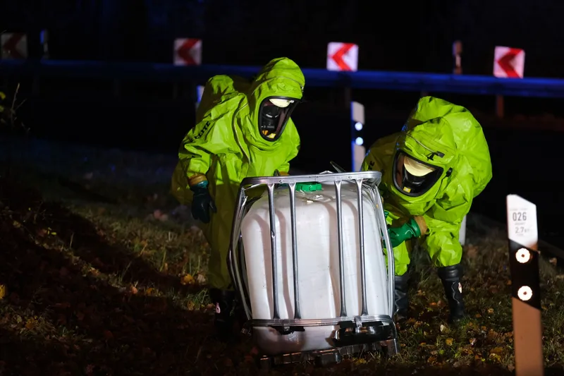 Spill response crew in protective suits recovering a leaking container
